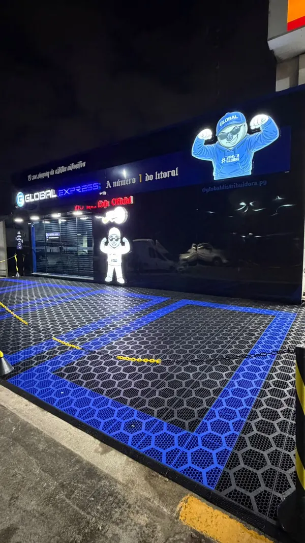 Fachada do Global Express em Santos à noite, com o letreiro e o mascote iluminados